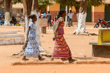 CANCHUNGO, GUINEA BISSAU - MAY 3, 2017: Unidentified local women walk beside the road in the centre of Canchungo, one of the major cities of the countryのeditorial素材