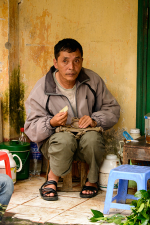 SAPA, VIETNAM - SEP 20, 2014: Unidentified Vietnamese man works at shop. Most of people of Vietnam belong to the Kinh (Viet) ethnic grop - 85.7%のeditorial素材