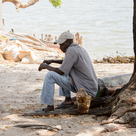 KASCHOUANE, SENEGAL - APR 29, 2017: Unidentified Diola man sits on the ground in Kaschouane village. Diolas are the ethnic group predominate in the region of Casamanceのeditorial素材