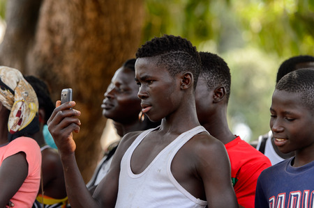 ORANGO ISLAND, GUINEA BISSAU - MAY 3, 2017: Unidentified local boy in white shirt holds a cellphone in his hand in the Etigoca village. People in G.-Bissau still suffer of povertyのeditorial素材