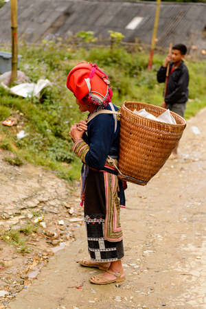 TA PHIN, LAO CAI, VIETNAM - SEP 21, 2014: Unidentified Red Dao woman in a red turban carries stuff to sell in the Ta Phin village. Red Dao is one of the minority ethnic groups in Vietnamのeditorial素材