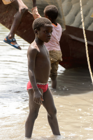 CANHABAQUE, GUINEA BISSAU - MAY 4, 2017: Unidentified local little boy stands in the water in a village of the Canhabaque island. People in G.-Bissau still suffer of povertyのeditorial素材