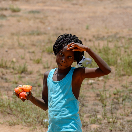 CANCHUNGO, GUINEA BISSAU - MAY 3, 2017: Unidentified local little girl in blue dress collects...