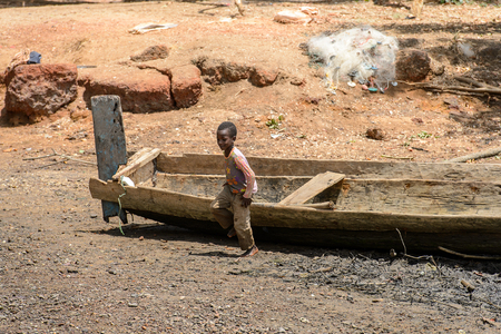 CANHABAQUE, GUINEA BISSAU - MAY 4, 2017: Unidentified local little boy walks near the boat in a village of the Canhabaque island. People in G.-Bissau still suffer of povertyのeditorial素材