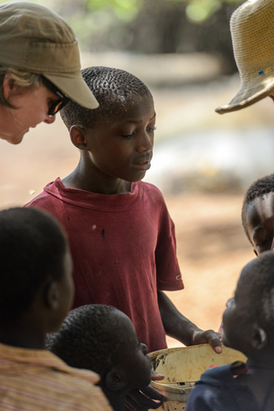 CANHABAQUE, GUINEA BISSAU - MAY 4, 2017: Unidentified local little boy in red shirt holds a bucket in a village of the Canhabaque island. People in G.-Bissau still suffer of povertyのeditorial素材