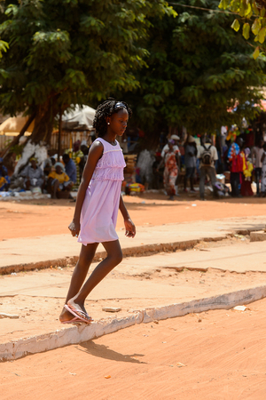 CANCHUNGO, GUINEA BISSAU - MAY 3, 2017: Unidentified local woman in pink dress walks in the centre of Canchungo, one of the major cities of the countryのeditorial素材