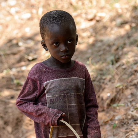 CANHABAQUE, GUINEA BISSAU - MAY 4, 2017: Unidentified local little boy holds a bucket in a village of the Canhabaque island. People in G.-Bissau still suffer of povertyのeditorial素材