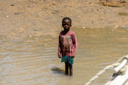 CANHABAQUE, GUINEA BISSAU - MAY 4, 2017: Unidentified local little boy stands in the water in a village of the Canhabaque island. People in G.-Bissau still suffer of povertyのeditorial素材