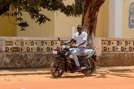 CANCHUNGO, GUINEA BISSAU - MAY 3, 2017: Unidentified local man rides a motorcycle in the centre of Canchungo, one of the major cities of the countryのeditorial素材