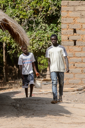 CANHABAQUE, GUINEA BISSAU - MAY 4, 2017: Unidentified local boys walk along the street in a village of the Canhabaque island. People in G.-Bissau still suffer of povertyのeditorial素材