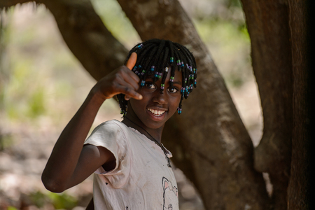 CANCHUNGO, GUINEA BISSAU - MAY 3, 2017: Unidentified local little girl with braids smile. Bissau-Guinean people suffer of poverty due to the bad economyのeditorial素材