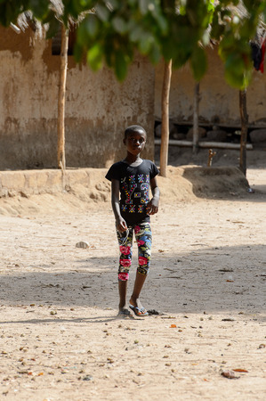 CANHABAQUE, GUINEA BISSAU - MAY 4, 2017: Unidentified local little girl stands in the middle of the street in a village of the Canhabaque island. People in G.-Bissau still suffer of povertyのeditorial素材