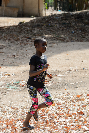 CANHABAQUE, GUINEA BISSAU - MAY 4, 2017: Unidentified local little girl runs along the street in a village of the Canhabaque island. People in G.-Bissau still suffer of povertyのeditorial素材