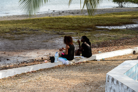 QUINHAMEL, GUINEA BISSAU - MAY 3, 2017: Unidentified local two women rest from behind on the coast of the Atlantic ocean in Quinhamel, a popular resort areaのeditorial素材