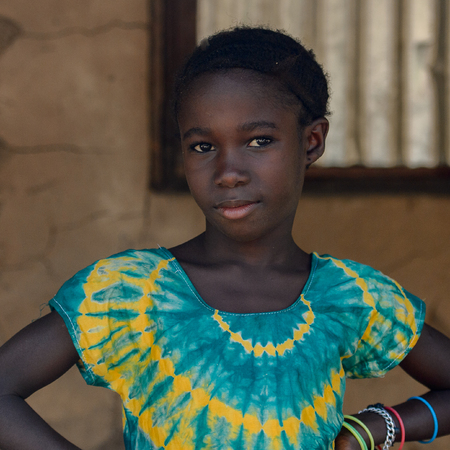 CANHABAQUE, GUINEA BISSAU - MAY 4, 2017: Unidentified local girl in colored shirt with braids smiles in a village of the Canhabaque island. People in G.-Bissau still suffer of povertyのeditorial素材