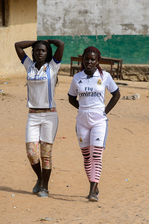ORANGO ISLAND, GUINEA BISSAU - MAY 3, 2017: Unidentified local women walk along the street in the Etigoca village. People in G.-Bissau suffer of poverty due to the bad economyのeditorial素材