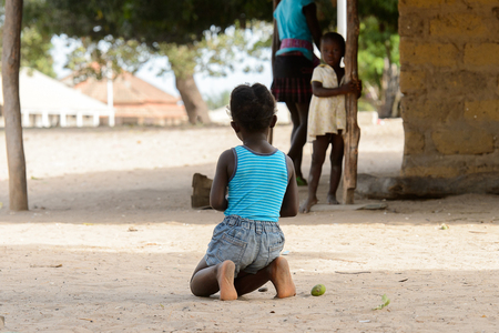 ORANGO ISLAND, GUINEA BISSAU - MAY 3, 2017: Unidentified local little girl squats in the Etigoca village. People in G.-Bissau suffer of poverty due to the bad economyのeditorial素材