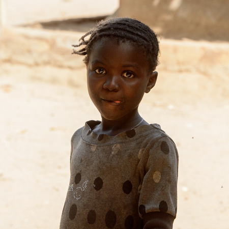 CANHABAQUE, GUINEA BISSAU - MAY 4, 2017: Unidentified local little girl stands in the middle of the street in a village of the Canhabaque island. People in G.-Bissau still suffer of povertyのeditorial素材