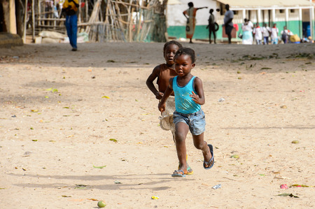 ORANGO ISLAND, GUINEA BISSAU - MAY 3, 2017: Unidentified local children run along the road in the Etigoca village. People in G.-Bissau suffer of poverty due to the bad economyのeditorial素材