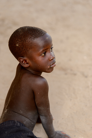 ORANGO ISLAND, GUINEA BISSAU - MAY 3, 2017: Unidentified local little boy sits in the sand in the Etigoca village. People in G.-Bissau suffer of poverty due to the bad economyのeditorial素材