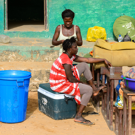 ORANGO ISLAND, GUINEA BISSAU - MAY 3, 2017: Unidentified local woman makes braids to her friend in...