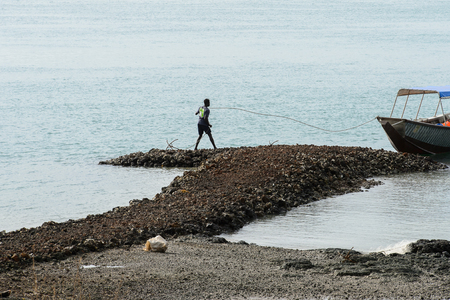 SOGA, GUINEA BISSAU - MAY 5, 2017: Unidentified local man holds a rope of anchor on the coast of the Soga island, part of the Bijagos Archipelagoのeditorial素材