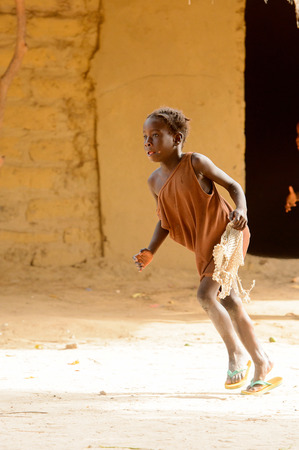 ORANGO ISLAND, GUINEA BISSAU - MAY 3, 2017: Unidentified local little girl runs along the street in the Etigoca village. People in G.-Bissau suffer of poverty due to the bad economyのeditorial素材