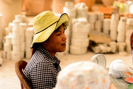 HANOI, VIETNAM - SEP 24, 2014: Unidentified Vietnamese woman draws on the ceramic dish in the ceramic workshop. Ceramic art is very popular in Asian cultureのeditorial素材