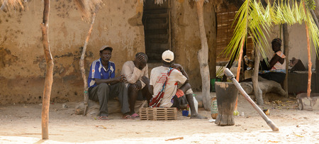 ORANGO ISLAND, GUINEA BISSAU - MAY 3, 2017: Unidentified local men sit in the shadow in the Etigoca village. People in G.-Bissau suffer of poverty due to the bad economyのeditorial素材