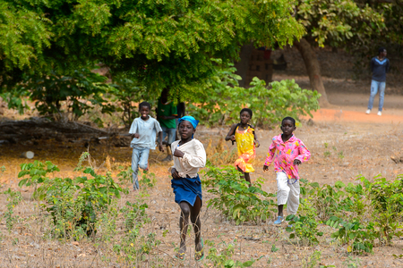 SOGA, GUINEA BISSAU - MAY 5, 2017: Unidentified local children run along the on the sand in a village of the Soga island. People in G.-Bissau still suffer of povertyのeditorial素材
