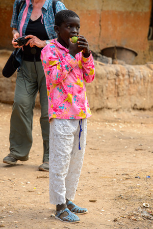 SOGA, GUINEA BISSAU - MAY 5, 2017: Unidentified local boy in colored shirt eats some fruit in a village of the Soga island. People in G.-Bissau still suffer of povertyのeditorial素材