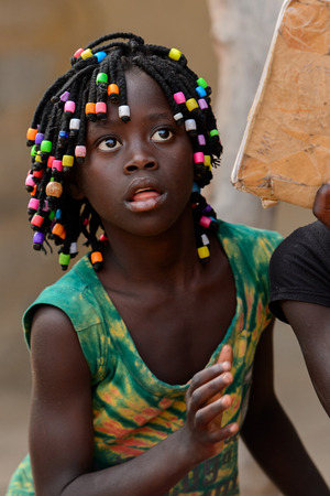 ORANGO ISLAND, GUINEA BISSAU - MAY 3, 2017: Unidentified local little girl with braids opens her mouth in the Etigoca village. People in G.-Bissau suffer of poverty due to the bad economyのeditorial素材