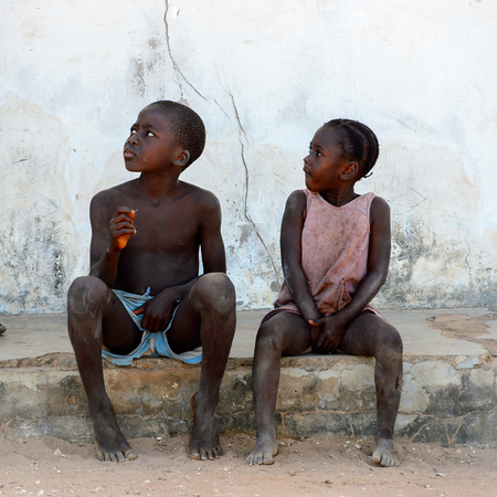 BUBAQUE, GUINEA BISSAU - MAY 5, 2017: Unidentified local little children sit at the causeway in a village of the Bubaque island. People in G.-Bissau still suffer of povertyのeditorial素材