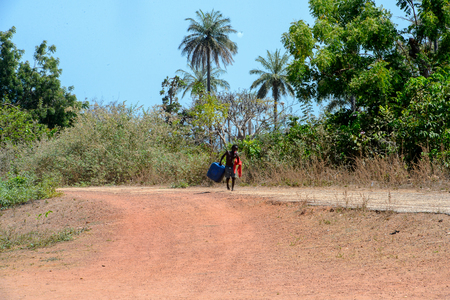 BUBAQUE, GUINEA BISSAU - MAY 5, 2017: Unidentified local boy carries a jerrycan in a village of the Bubaque island. People in G.-Bissau still suffer of povertyのeditorial素材
