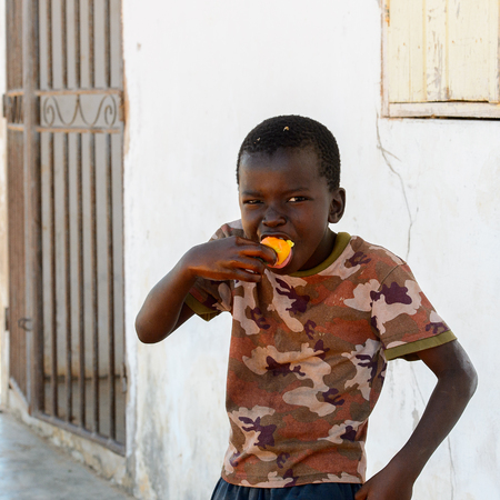BUBAQUE, GUINEA BISSAU - MAY 5, 2017: Unidentified local little boy holds some fruit in his hand and smiles in a village of the Bubaque island. People in G.-Bissau still suffer of povertyのeditorial素材