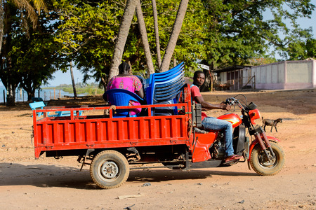 BOLAMA ISLAND, GUINEA BISSAU - MAY 6, 2017: Unidentified local man rides a tricycle along the street in the ghost town of Bolama, the former capital of Portuguese Guineaのeditorial素材