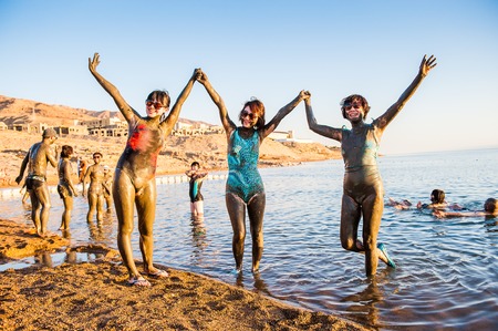 DEAD SEA RESORT, JORDAN - APR 30, 2014: Unidentified Chinese tourists pose in the mud of the Dead...
