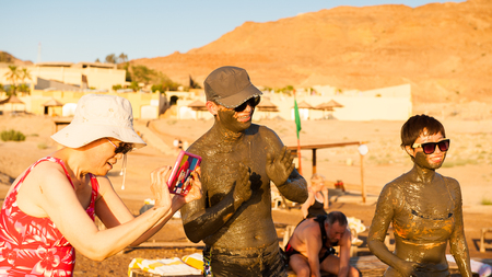 DEAD SEA RESORT, JORDAN - APR 30, 2014: Unidentified Chinese tourists in the mud of the Dead Sea. Dead Sea mud posesses the medical qualities and helps to the people with skin problemsのeditorial素材