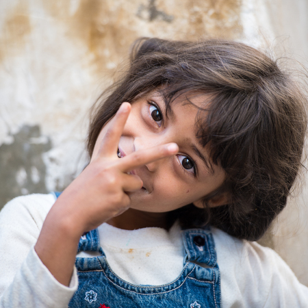 SANA'A, YEMEN - JAN 11, 2014: Unidentified Yemeni little girl shows Victory sign in the street in Sana'a. Children of Yemen grow up without educationのeditorial素材
