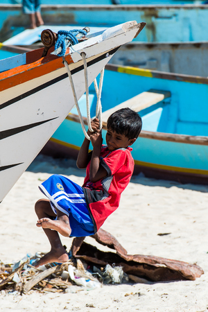 SOCOTRA, YEMEN - JAN 12, 2014: Unidentified Yemeni little boy plays hanging on a boat on the beach of the Island of Socotra. Children in Socotra live in poverty and grow without educationのeditorial素材