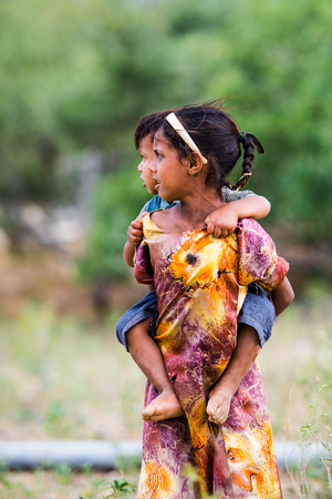 SOCOTRA, YEMEN - JAN 14, 2014: Unidentified Yemeni girl carries her little brother on her back on the Socotra Archipelago. Children on the  Socotra Archipelago grow without educationのeditorial素材