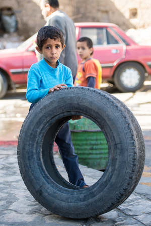SANA'A, YEMEN - JAN 11, 2014: Unidentified Yemeni boy plays with a tyre in the street in Sana'a. Children of Yemen grow up without educationのeditorial素材