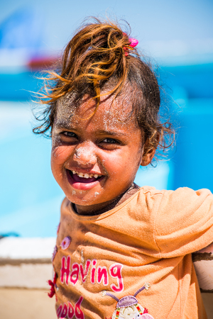 SOCOTRA, YEMEN - JAN 12, 2014: Unidentified Yemeni little girl with sand on her face plays on the beach of the Island of Socotra. Children in Socotra live in poverty and grow without educationのeditorial素材