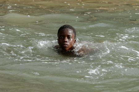 RUBANE, GUINEA BISSAU - MAY 4, 2017: Unidentified local boy swims in water during a high tideのeditorial素材