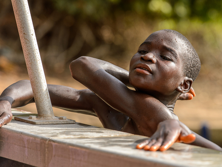 RUBANE, GUINEA BISSAU - MAY 4, 2017: Unidentified local  boy leans on the edge of the boat during a high tideのeditorial素材
