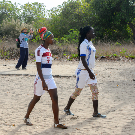 ORANGO ISLAND, GUINEA BISSAU - MAY 3, 2017: Unidentified local women in headscarf and braids walk after a physical culture lesson on the Orange islandのeditorial素材