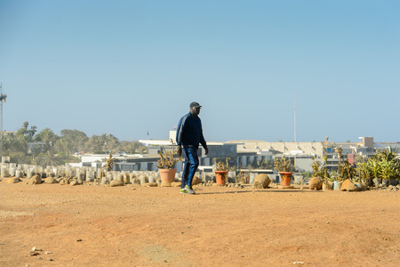 DAKAR, SENEGAL - APR 23, 2017: Unidentified Senegalese man in blue suit walks on the coast of the ocean in Dakar, the capital and main city of Senegalのeditorial素材