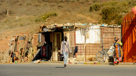 DAKAR, SENEGAL - APR 23, 2017: Unidentified Senegalese man in sunglasses and striped shirt walks along the road in Dakar, the capital and main city of Senegalのeditorial素材