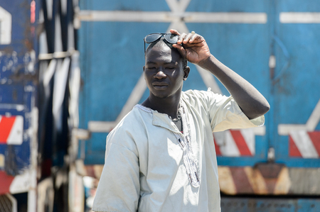 DAKAR, SENEGAL - APR 23, 2017: Unidentified Senegalese man in white shirt touches up his sunglasses in Dakar, the capital and main city of Senegalのeditorial素材