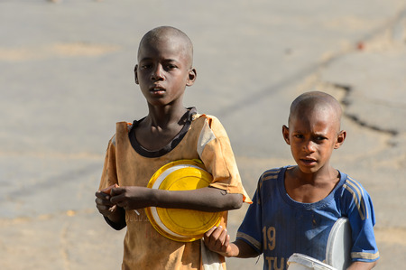 SAINT LOUIS, SENEGAL - APR 24, 2017: Unidentified Senegalese two little boys carry buckets in Saint...
